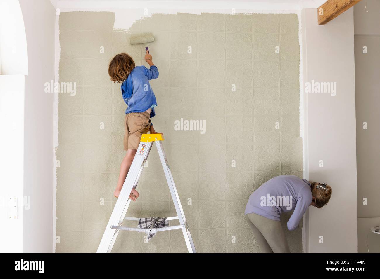 A woman and an eight year old boy decorating a room, painting walls. Stock Photo