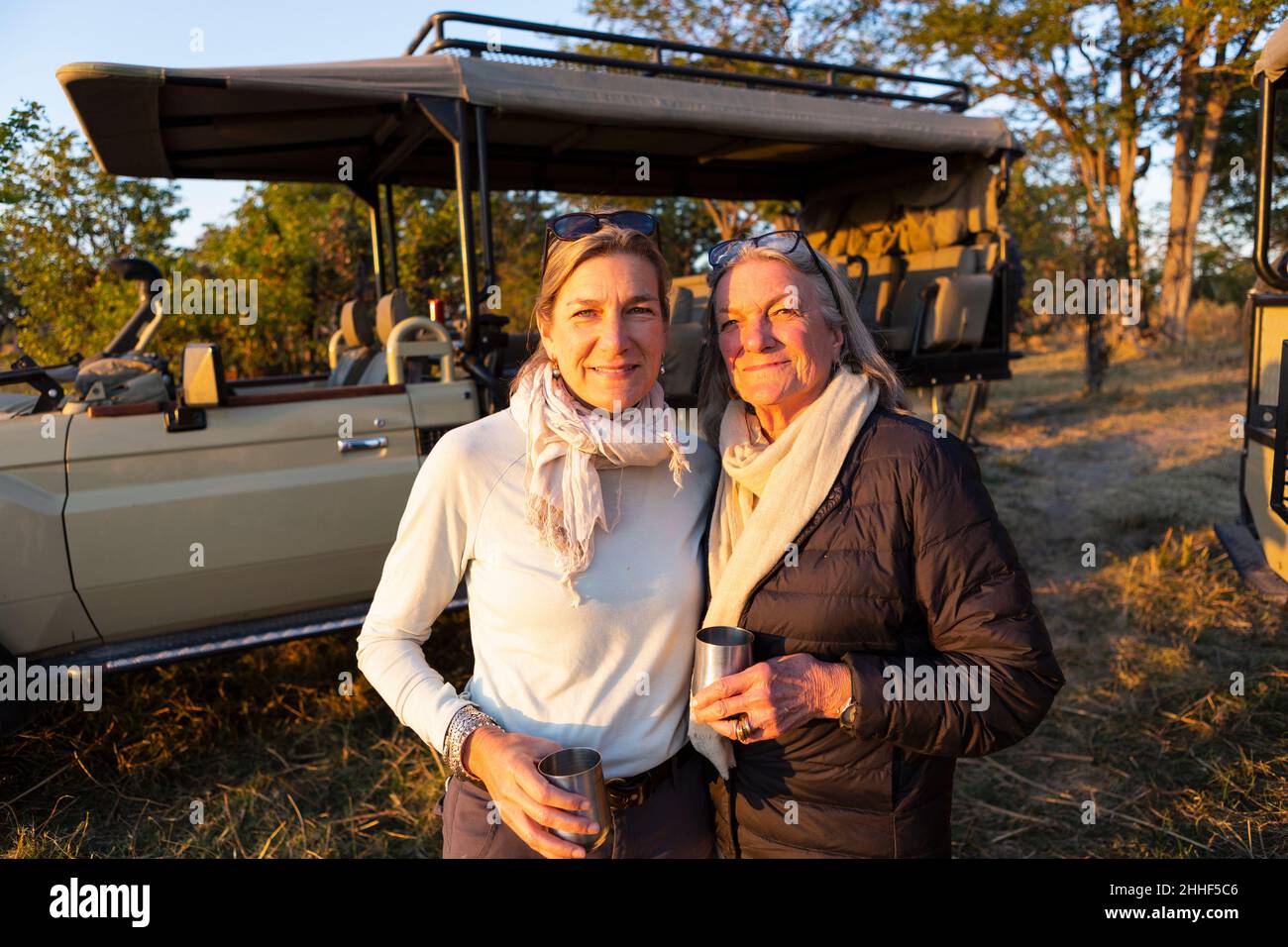 An adult woman and her mother standing side by side, by a jeep at sundown. Stock Photo