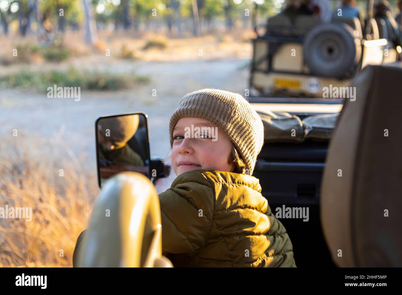 A boy sitting in a jeep on a safari drive at sunrise Stock Photo