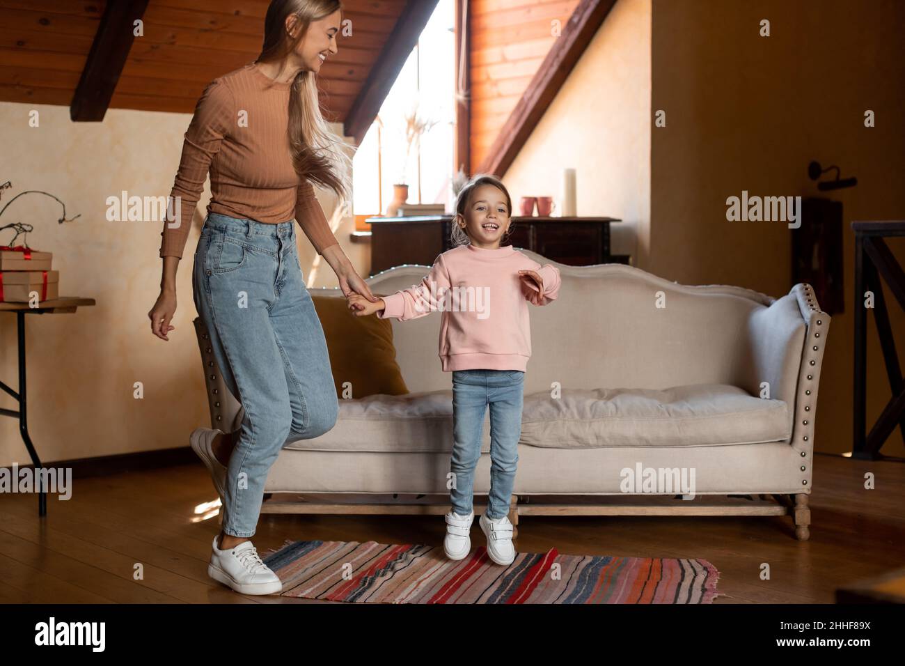 Positive mother dancing to music and jumping with little girl Stock ...
