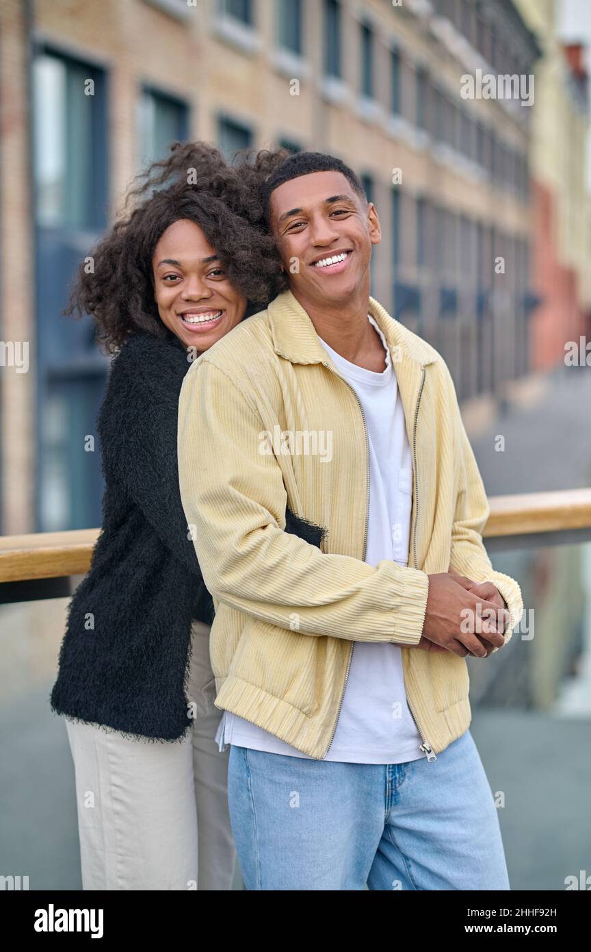 Woman hugging man looking at camera on bridge Stock Photo - Alamy