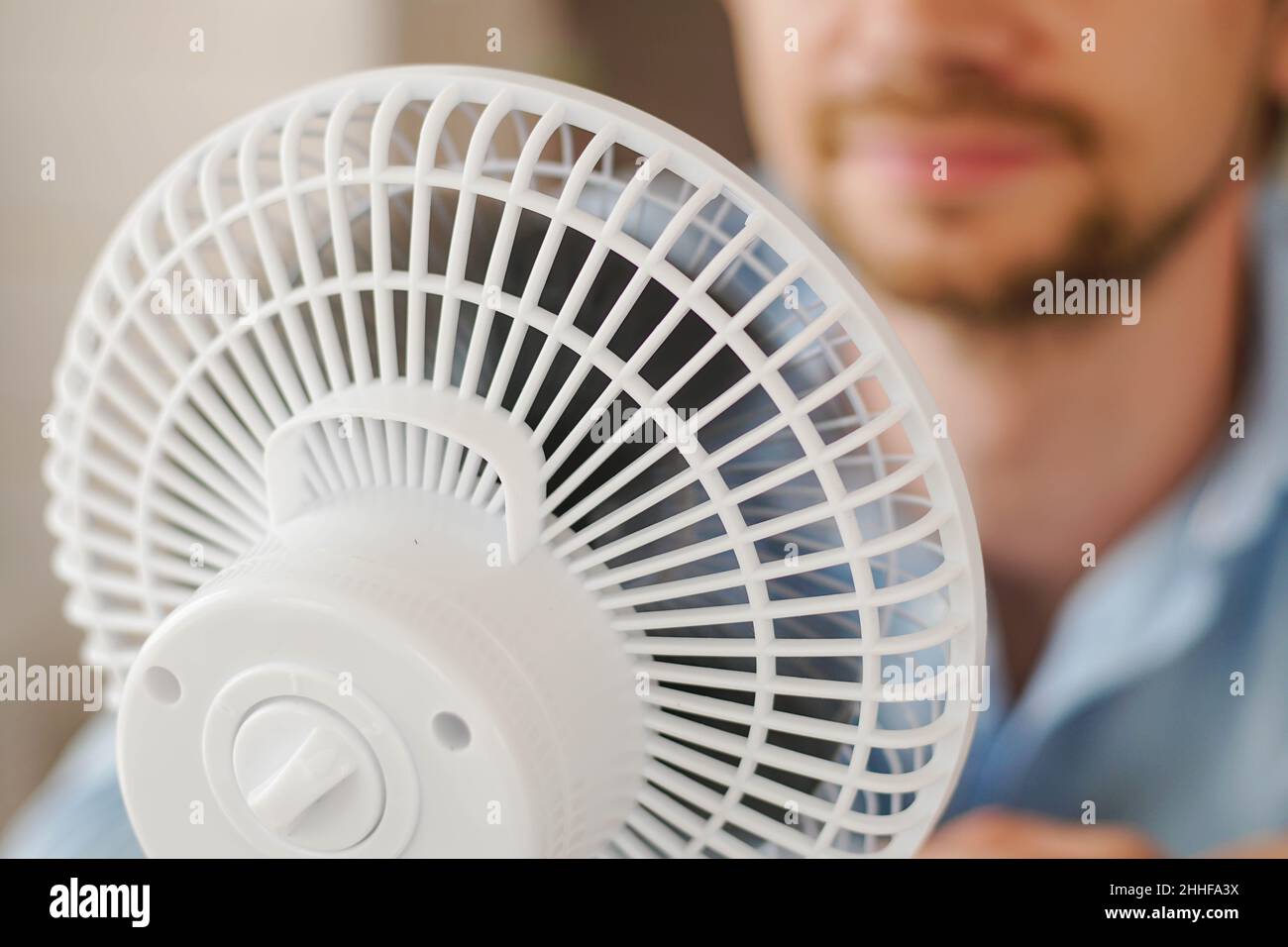 Man enjoying air flow from fan in office. Businessman refreshing in front of air electric ventilator. Summer heat. Stock Photo