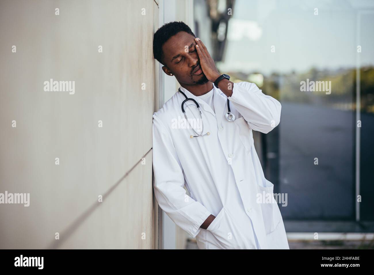 male doctor at the clinic holding his head has health problems and tired after a hard day, depressed did not get the desired result, afro american doc Stock Photo
