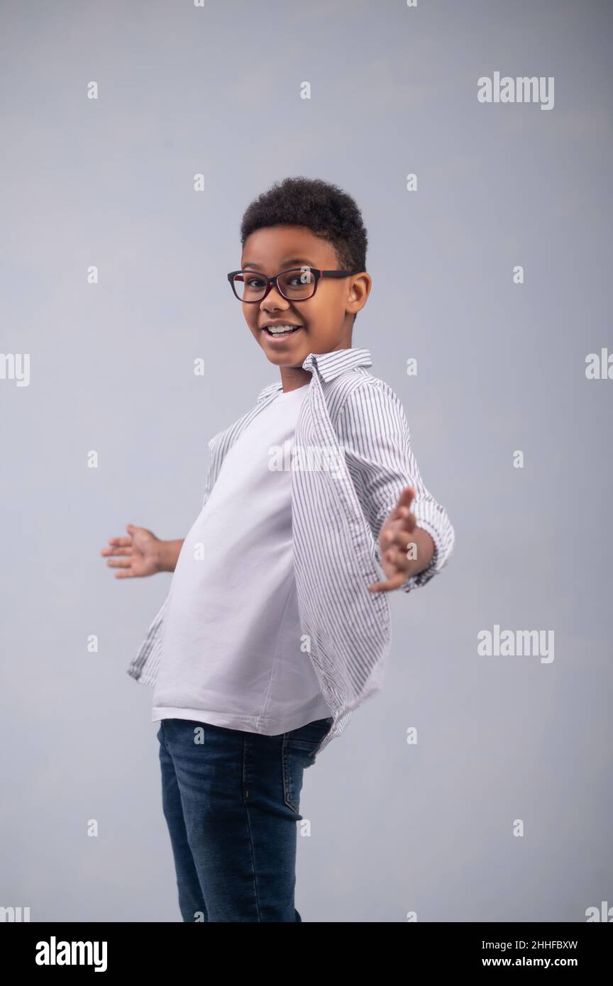 Kid in eyeglasses expressing his emotions through hand gestures Stock Photo