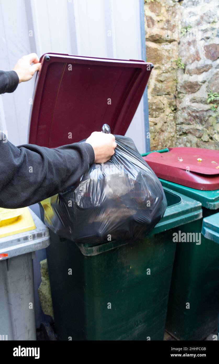 Put the trash bag in the garbage bin of a building Stock Photo