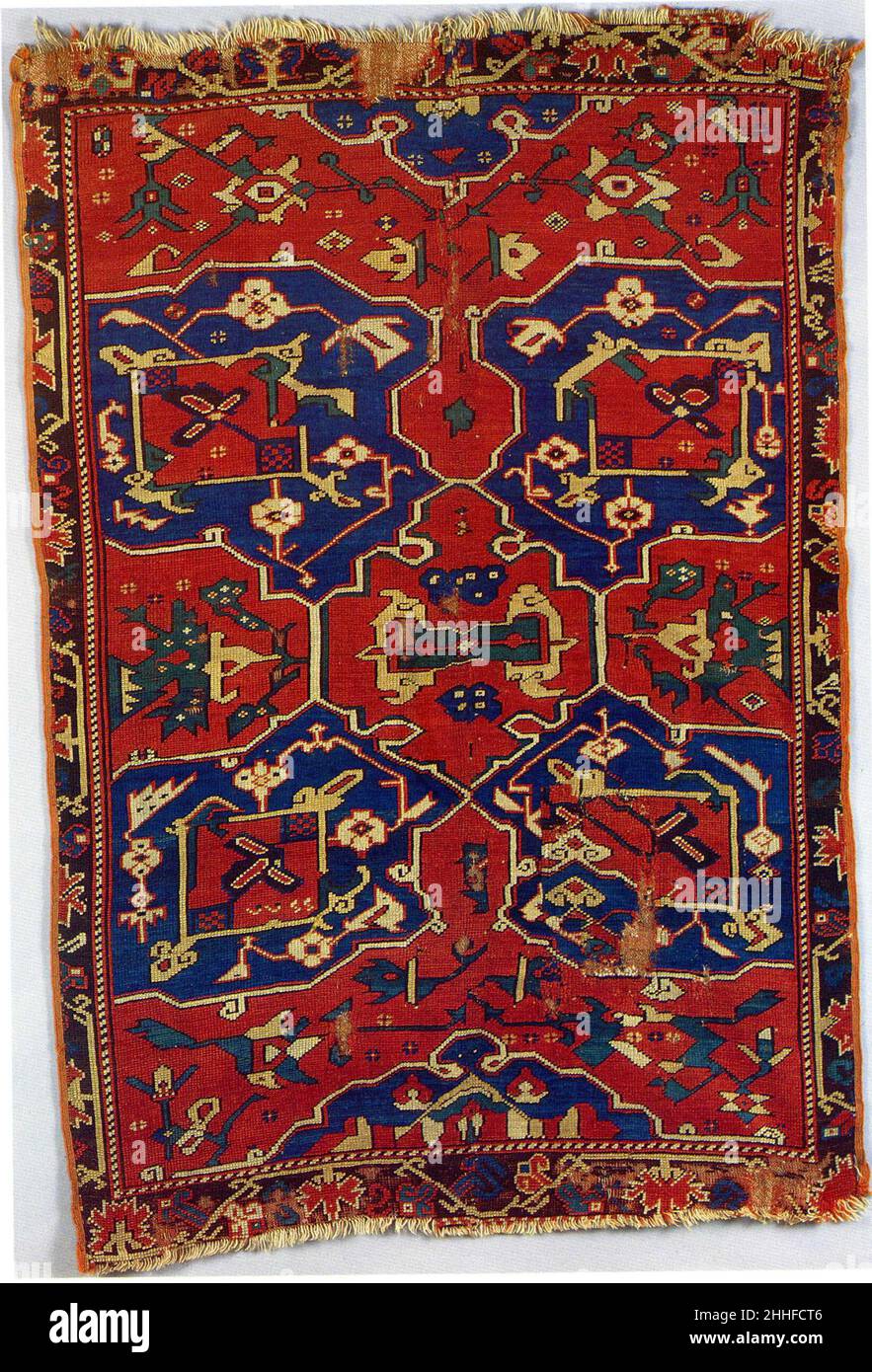Carpet with Quatrefoil Design probably 18th century This small carpet shows a large quatrefoil design in dark blue on a red ground that stretches across the entire width of the center field, while partial cartouche-like medallions fill the upper and lower-end edges of it. Various highly stylized floral motifs decorate the larger blue motifs and the red ground. The strong geometric rendering of the flowers makes their identification difficult. However, the comparison with earlier Ushak carpets with quatrefoil designs (see for example 1972.80.4), allows the viewer to distinguish lotus flowers, f Stock Photo