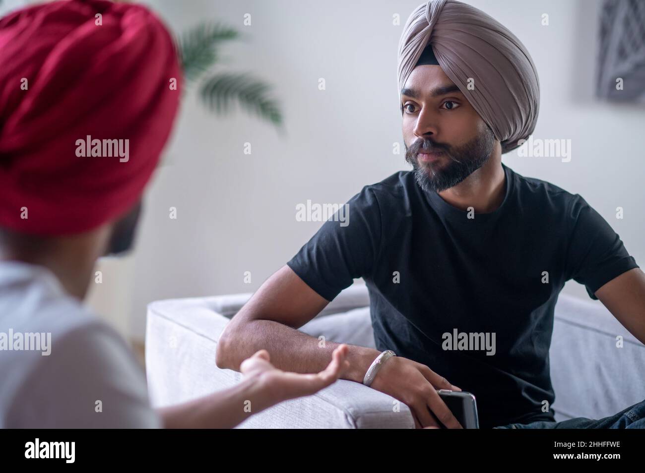 Two men in turbans talking and looking involved Stock Photo