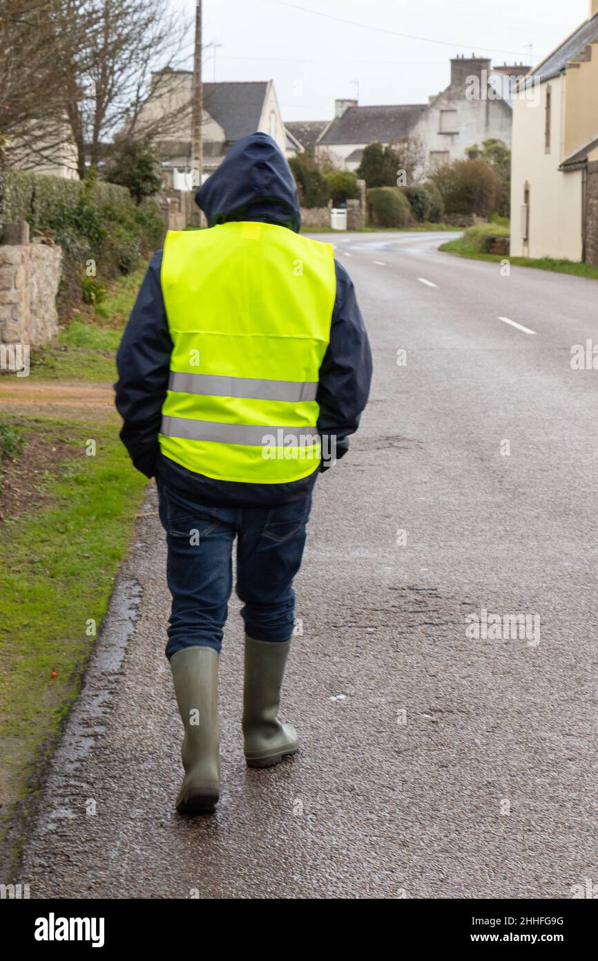 Man with yellow vest walking on the road Stock Photo - Alamy