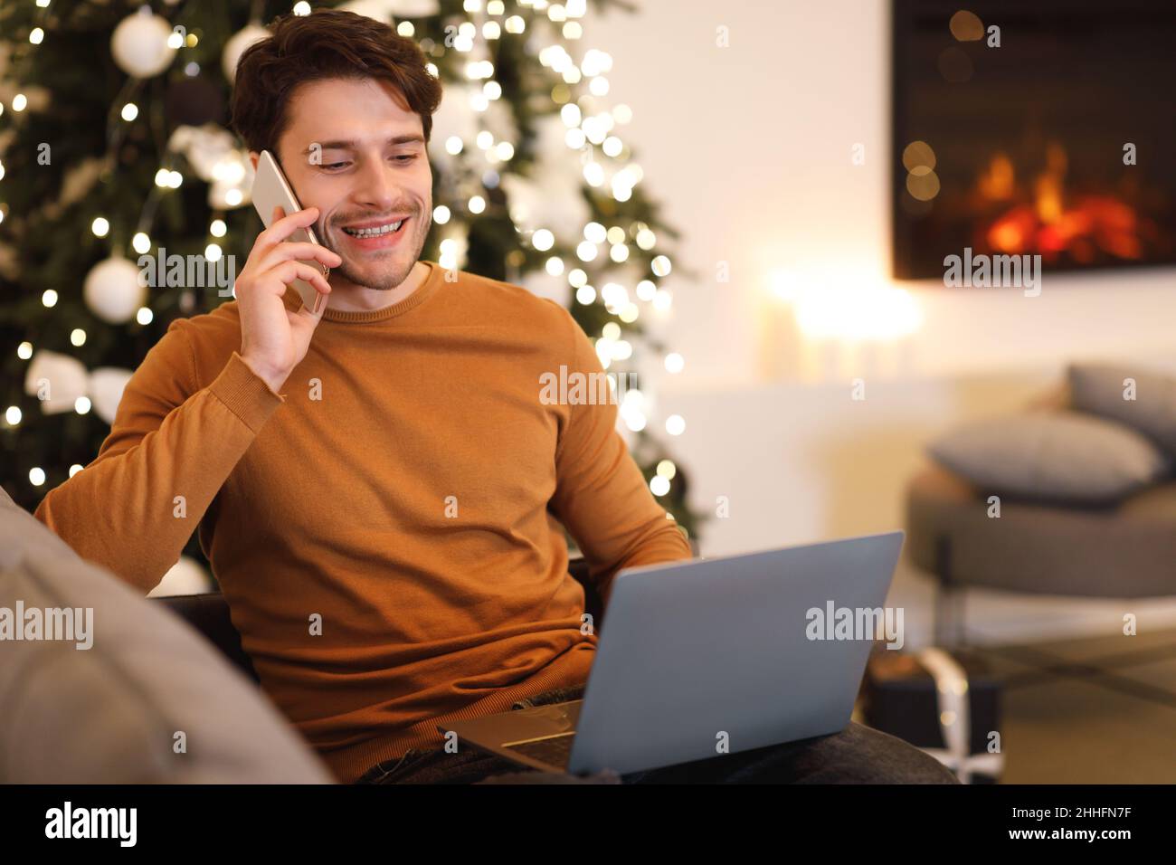 Cheerful man working and talking on cellphone using pc Stock Photo