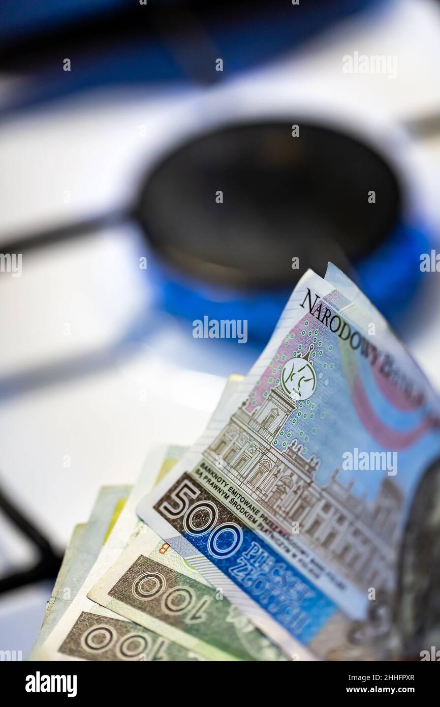 Polish banknotes against the background of a burning gas stove. Expensive gas fuel generates inflation in Poland. Photo taken in natural lighting cond Stock Photo