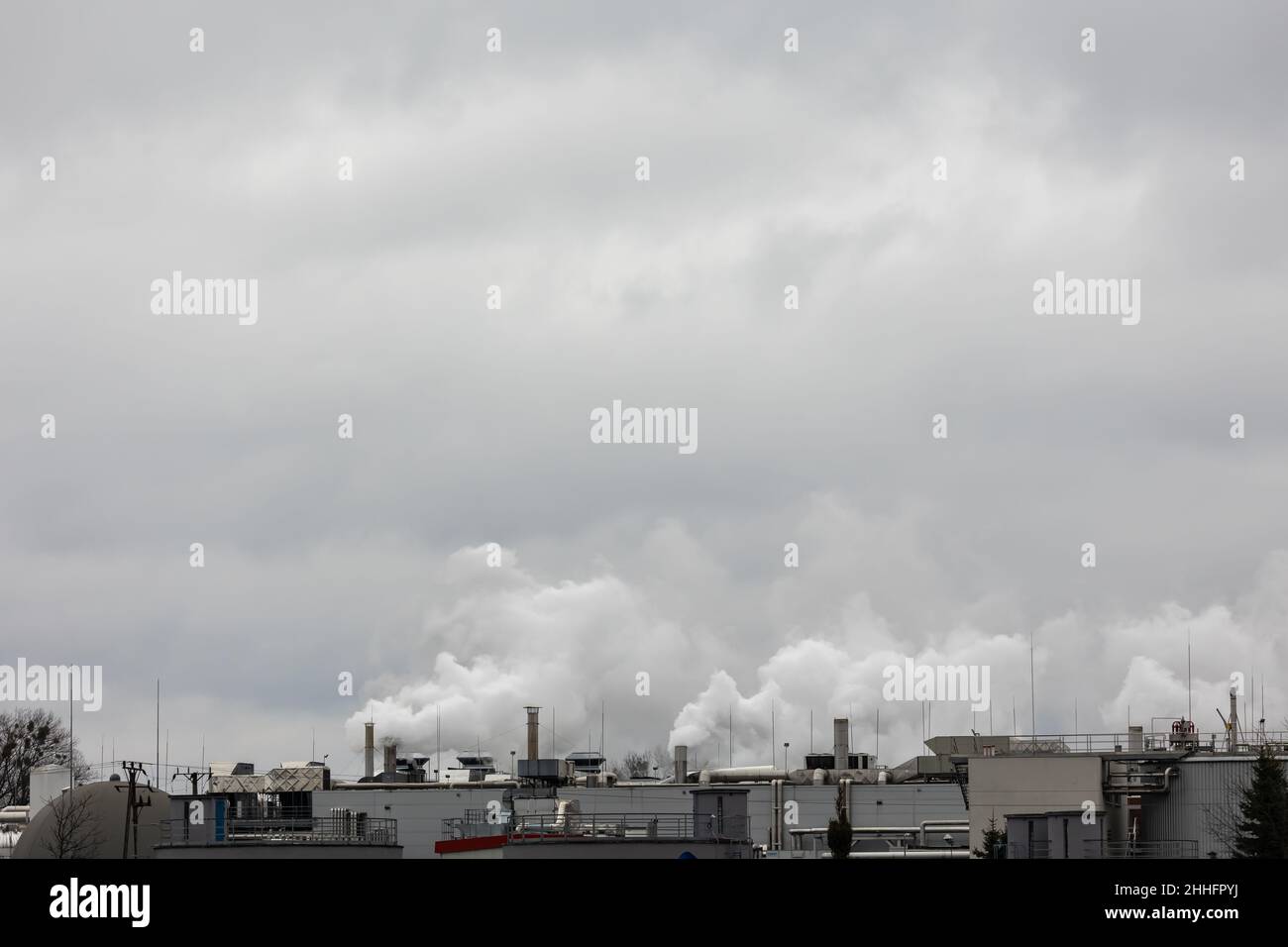 Puffs of steam coming out of chimneys on the roof of an industrial plant. Picture taken on a cloudy day, uniform and soft light. Stock Photo