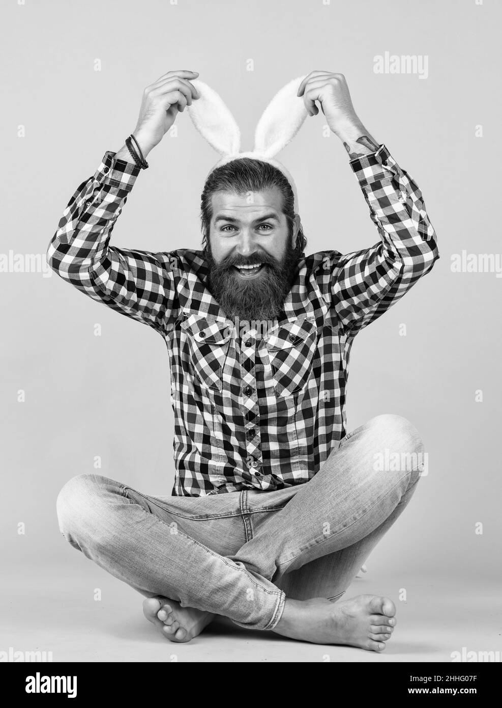 Caucasian mature hipster in buny ears with trendy hairstyle in checkered shirt celebrate easter, easter fun Stock Photo