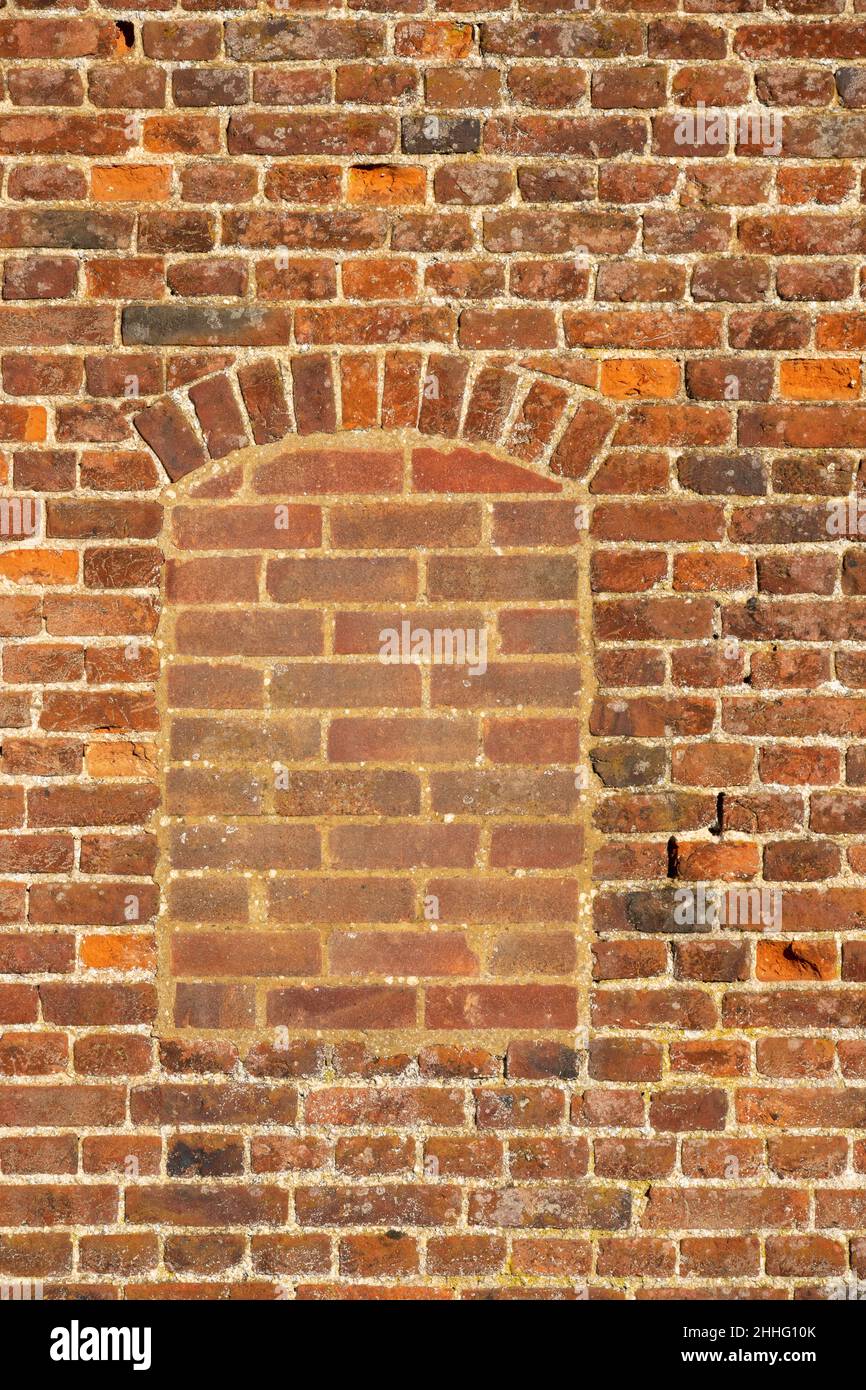 A flat on area of antique red brick wall with a filled in window Stock Photo