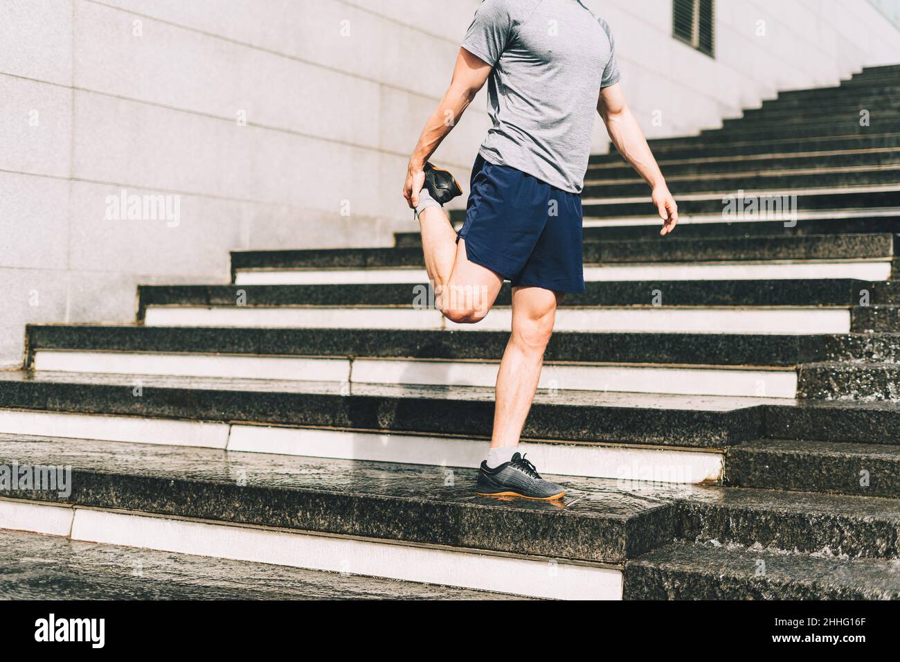 Young athlete man runner running up and down on city stairs in summer on morning run, background urban city street. Sports training. Fitness cardio Stock Photo
