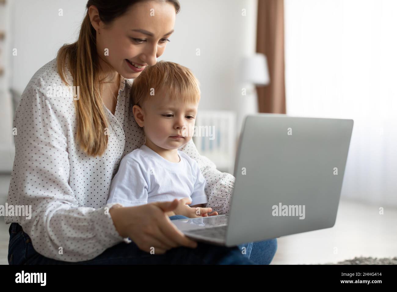 Happy single mother and little son using laptop online application, making video call or watching cartoons together Stock Photo