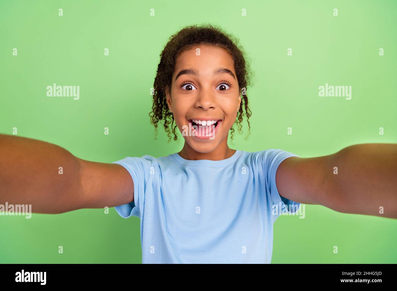 Photo of young african teen girl happy positive smile record video selfie blogger isolated over green color background Stock Photo
