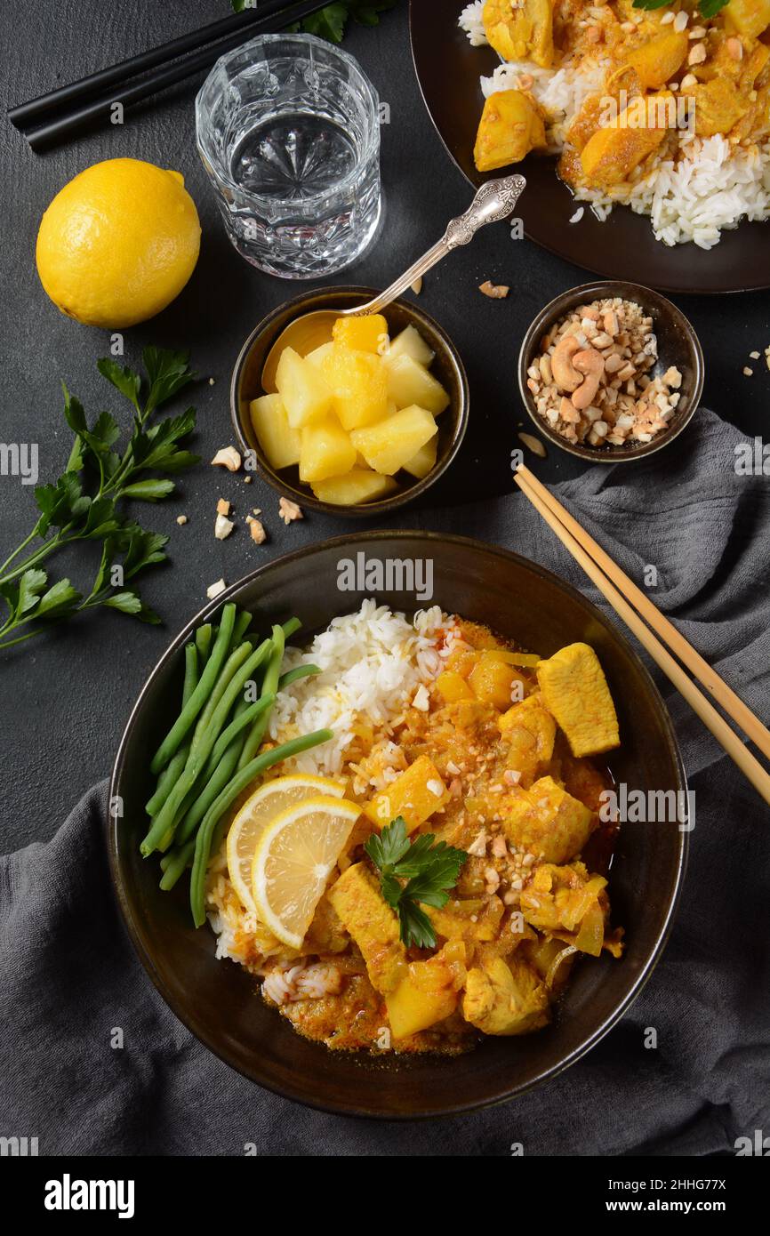 A Chicken Massaman Curry in black bowl at dark background. Massaman Curry is Thai Indian best dish with chicken meat, potato, onion and many spices is Stock Photo