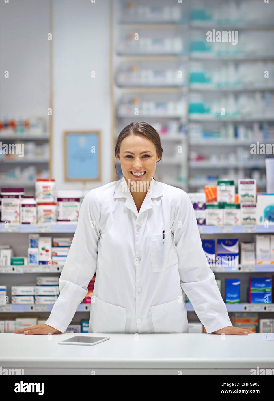 Providing prescriptions and a smile. Portrait of an attractive young pharmacist standing at the prescription counter. Stock Photo