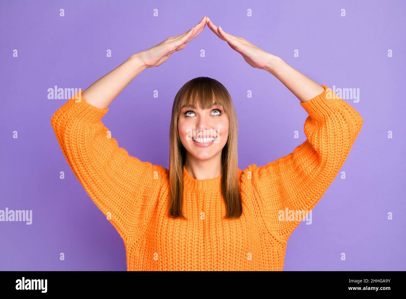Photo of lady raise hands roof form look up empty space wear orange sweater isolated violet color background Stock Photo