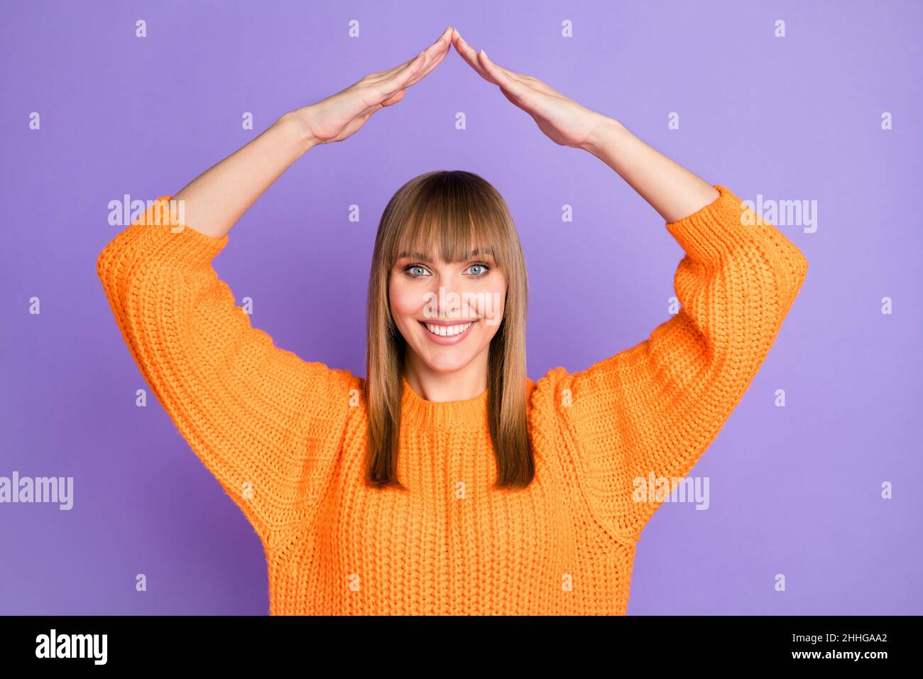 Photo of lady raise hands roof form shiny smile wear orange pullover isolated violet color background Stock Photo