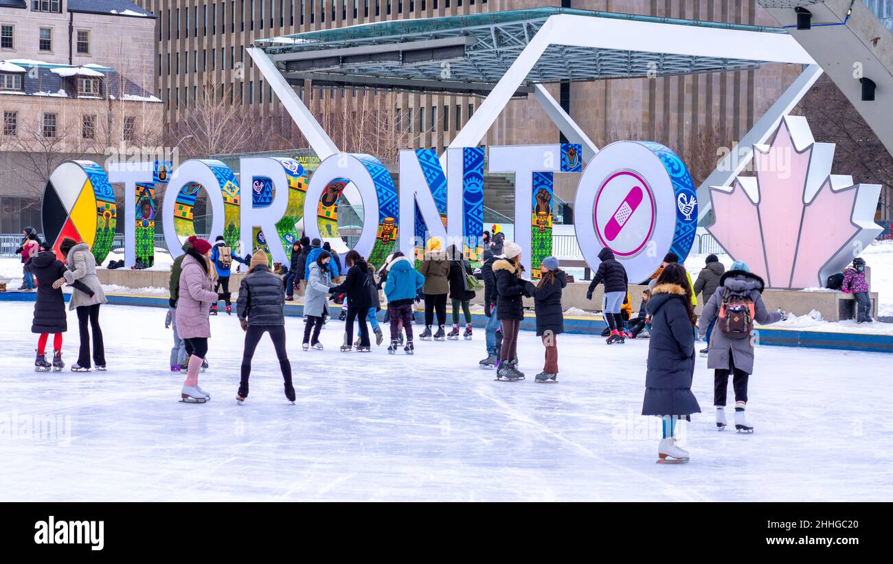 People skating in the Nathan Phillips Square rink during the Winter season. The Toronto 3D sign is seen in the background Stock Photo