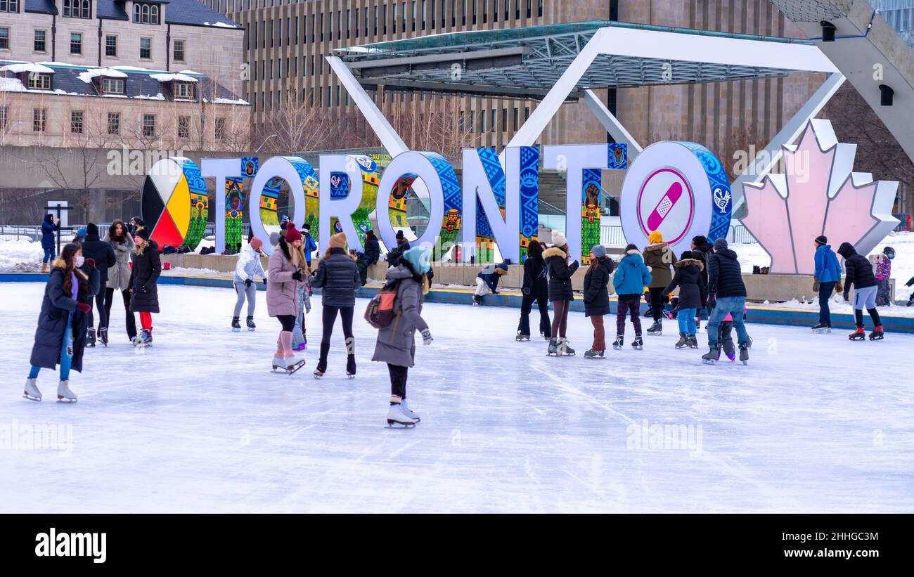 People skating in the Nathan Phillips Square rink during the Winter season. The Toronto 3D sign is seen in the background Stock Photo