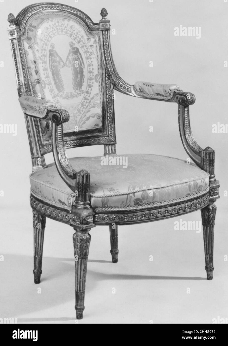 Armchair (fauteuil en cabriolet) (one of a pair) (part of a set) ca. 1785 Jean-Baptiste-Bernard Demay This pair of armchairs formerly belonged to the Marquise de Ganay just as the Neoclassical bergères à la reine by Demay also in the museum’s collection (1973.305.3). Made of carved and gilded beechwood, the armchairs have a slightly curved back. Two pinecone finials terminate the top rail while the decorative motifs of pearls and guilloches, acanthus scrolls, and columns are frequently found on Neoclassical furnishings created during the reign of Louis XVI. Seen together with the bergères (197 Stock Photo