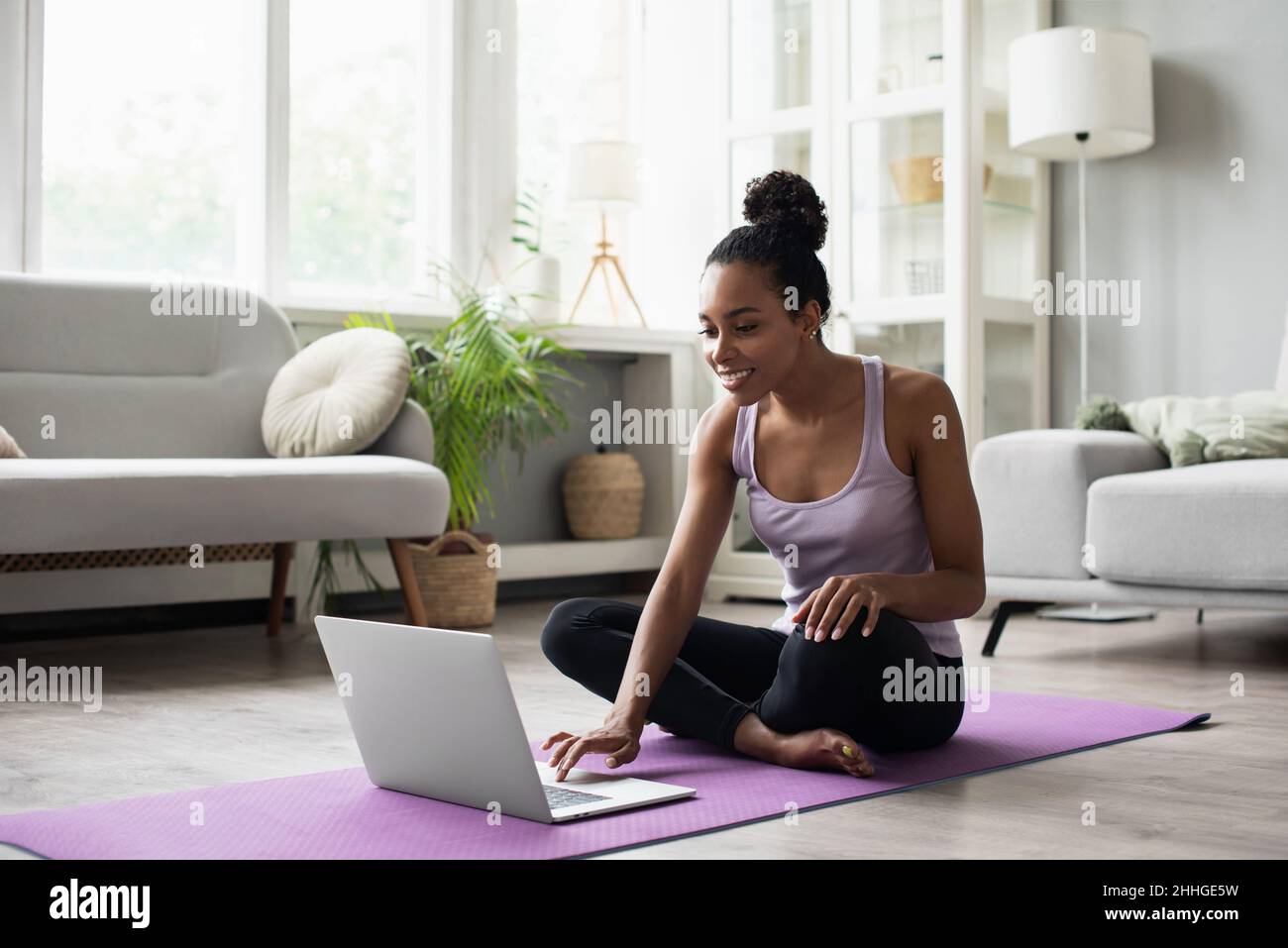 Young woman doing fitness exercises at home. Online video training. Meditation, relaxation, healthy lifestyle, self-care, online training class, yoga Stock Photo