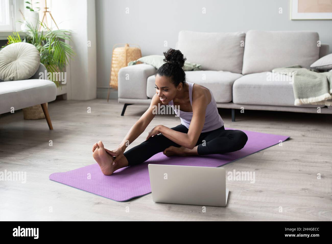 Young woman doing fitness exercises at home. Online video training. Meditation, relaxation, healthy lifestyle, self-care, online training class, yoga Stock Photo