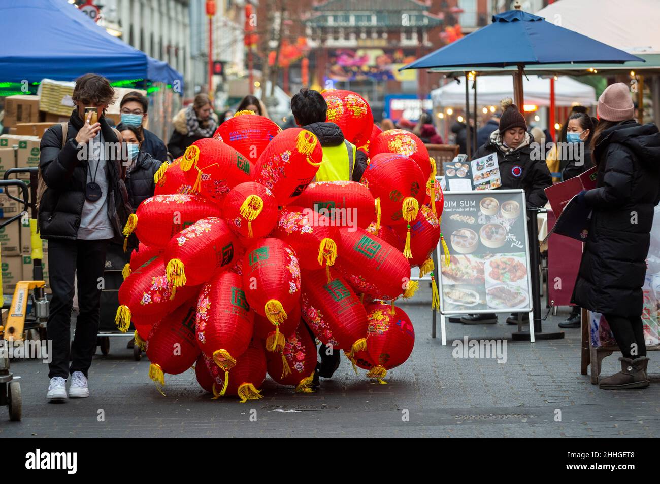 London, UK.  24 January 2022.   A workman carries assembled lanterns in Chinatown ahead of Chinese New Year and The Year of the Tiger officially begins on 1 February.  Festivities on Chinatown are scaled back this year to the pandemic.  Credit: Stephen Chung / Alamy Live News Stock Photo