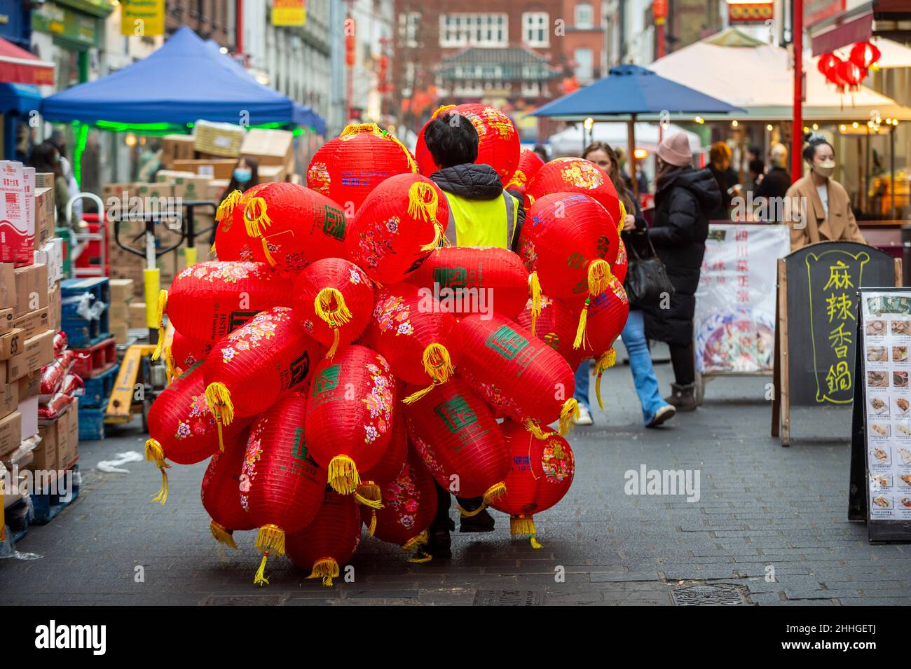 London, UK.  24 January 2022.   A workman carries assembled lanterns in Chinatown ahead of Chinese New Year and The Year of the Tiger officially begins on 1 February.  Festivities on Chinatown are scaled back this year to the pandemic.  Credit: Stephen Chung / Alamy Live News Stock Photo
