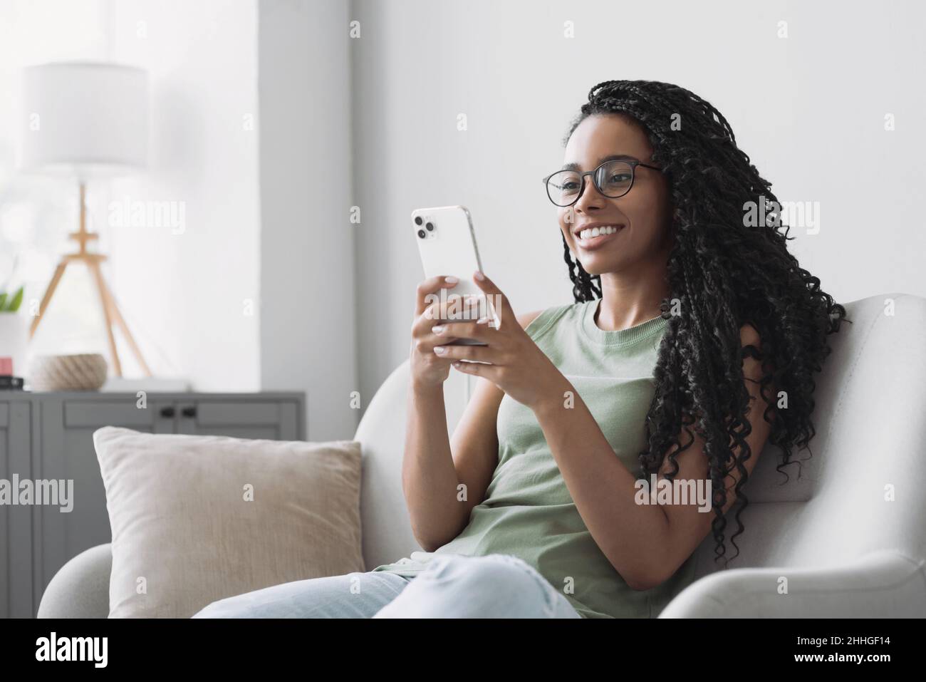 Woman using smartphone at home. Young woman looking at mobile phone. Mobile apps, technology, lockdown, web chat, lifestyle concept Stock Photo