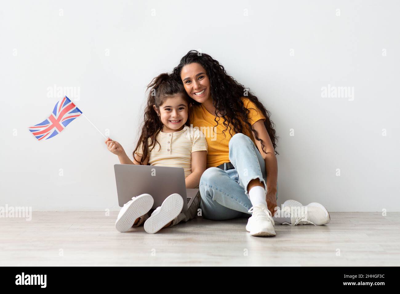 Online Visa Application. Mom And Little Daughter With British Flag And Laptop Stock Photo