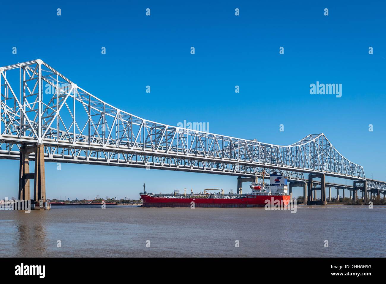 Port of New Orleans on the Mississippi River with a boat, ship, barge, passing under the Mississippi River Bridge, Louisiana, USA. Stock Photo