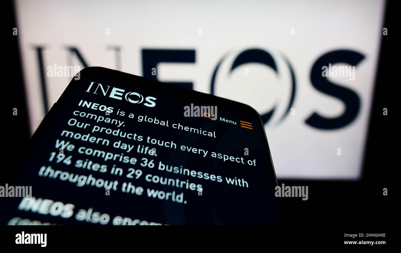 Mobile phone with website of British chemicals company INEOS Group Ltd. on screen in front of business logo. Focus on top-left of phone display. Stock Photo