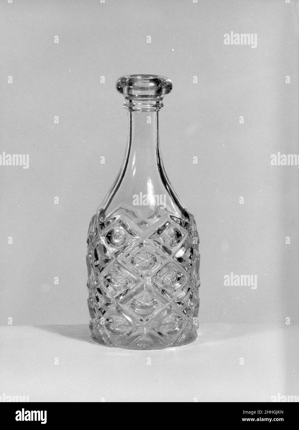 Half-pint Decanter 1850–70 American With the development of new formulas and techniques, glass-pressing technology had improved markedly by the late 1840s. By this time, pressed tablewares were being produced in large matching sets and innumerable forms. During the mid-1850s, colorless glass and simple geometric patterns dominated. Catering to the demand for moderately-priced dining wares, the glass industry in the United States expanded widely, and numerous factories supplied less expensive pressed glassware to the growing market. At the Exhibition of the Industry of All Nations at New York’s Stock Photo