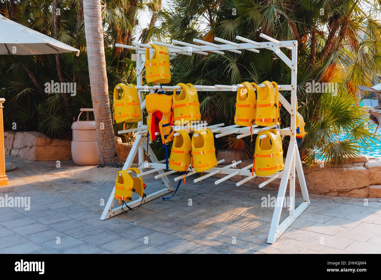 Stack of hanging yellow life vests on hangers outside during the marine activities, safety clothing, protection concept. Stock Photo