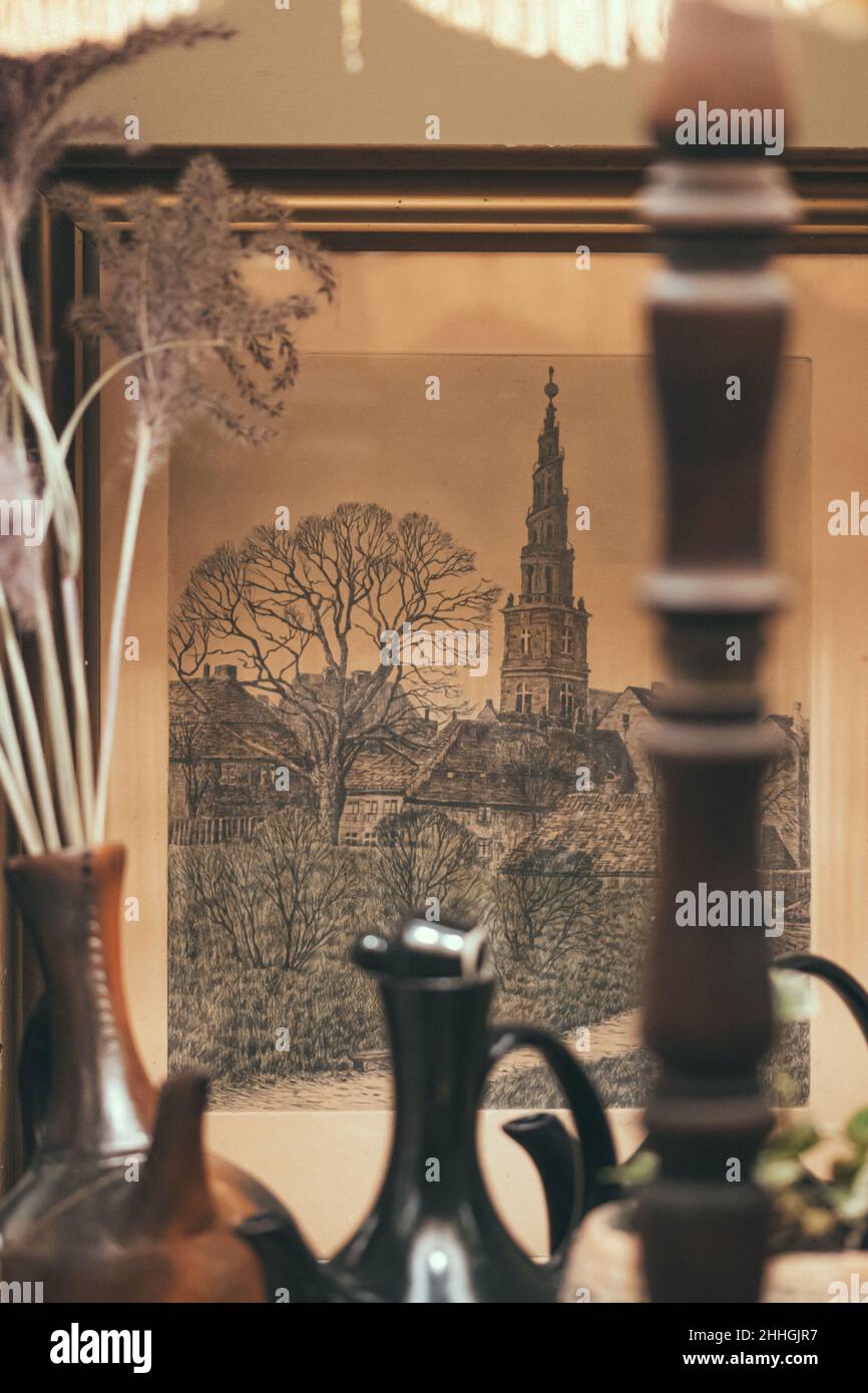 Ancient lithography depicting The Church of Our Savior, a baroque church in Copenhagen, Denmark in an old frame with vintage vases and lamp, vertical Stock Photo