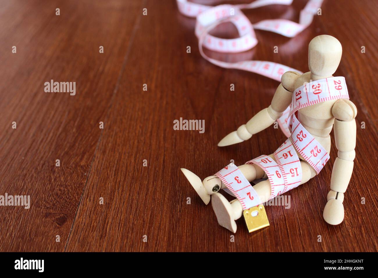 Weight management, diet concept. Wooden doll and measuring tape with copy space for text. Stock Photo