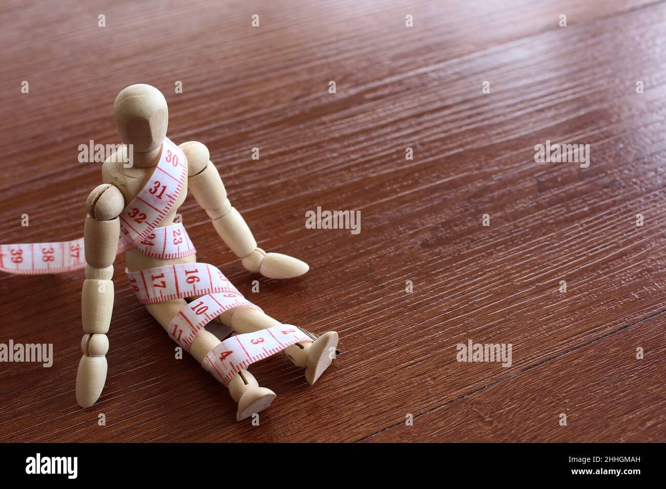 Weight management, diet concept. Wooden doll and measuring tape with copy space for text. Stock Photo