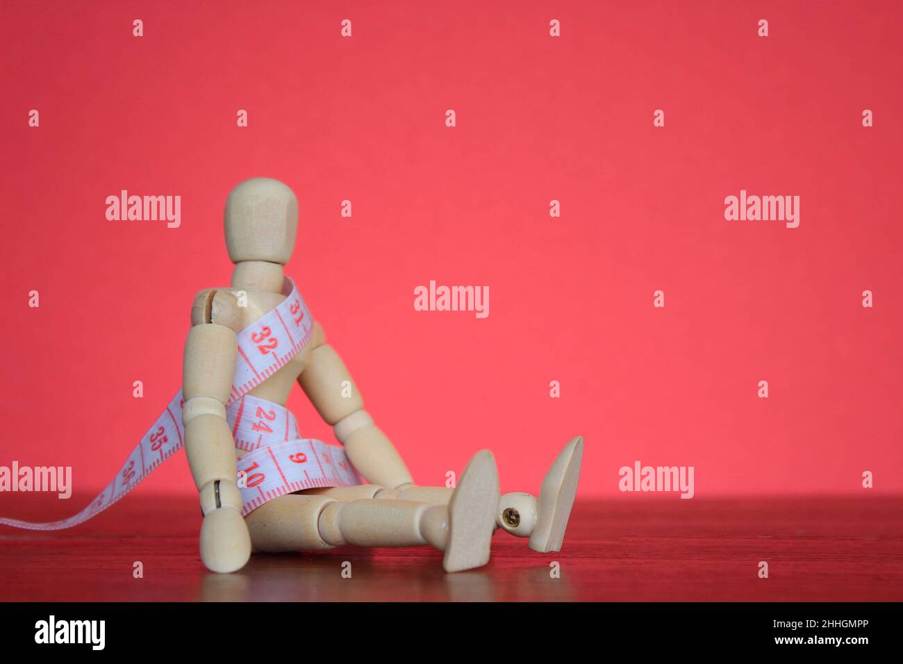 Weight management, diet concept. Wooden doll and measuring tape with copy space for text. Stock Photo