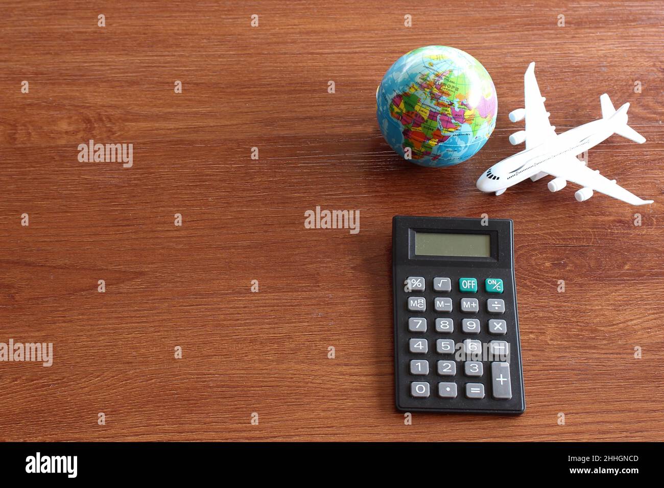 Travel cost calculation concept. Toy plane, earth globe and calculator on wooden table. Stock Photo