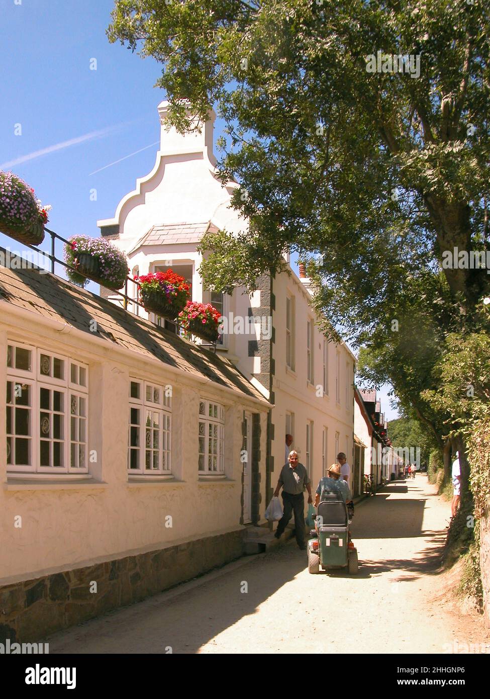 The Avenue, Sark's main street with shops and tourists in The Village, the centre of Sark, Bailiwick of Guernsey, Channel Islands. No cars or trucks are allowed on Sark. Stock Photo