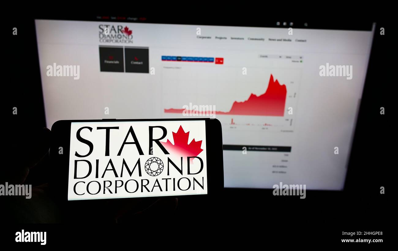 Person holding mobile phone with logo of Canadian mining company Star Diamond Corporation on screen in front of web page. Focus on phone display. Stock Photo
