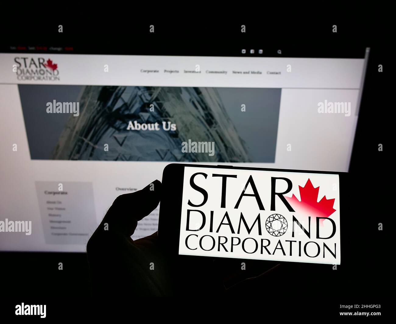 Person holding smartphone with logo of Canadian mining company Star Diamond Corporation on screen in front of website. Focus on phone display. Stock Photo