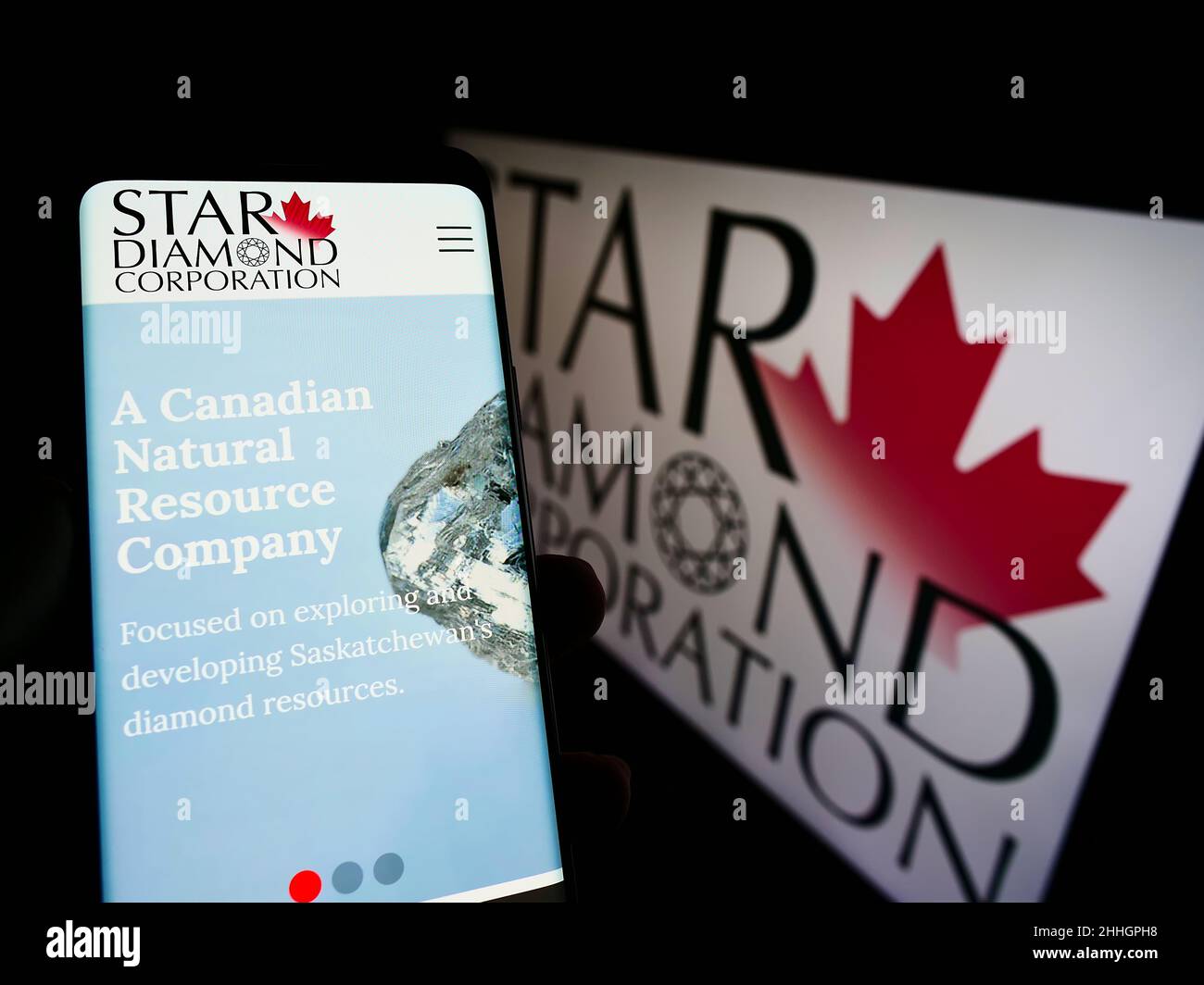 Person holding cellphone with website of Canadian mining company Star Diamond Corporation on screen with logo. Focus on center of phone display. Stock Photo