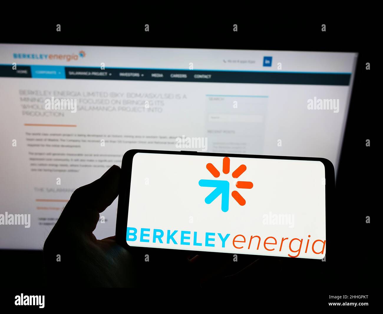 Person holding mobile phone with logo of British energy company Berkeley Energia Limited on screen in front of web page. Focus on phone display. Stock Photo