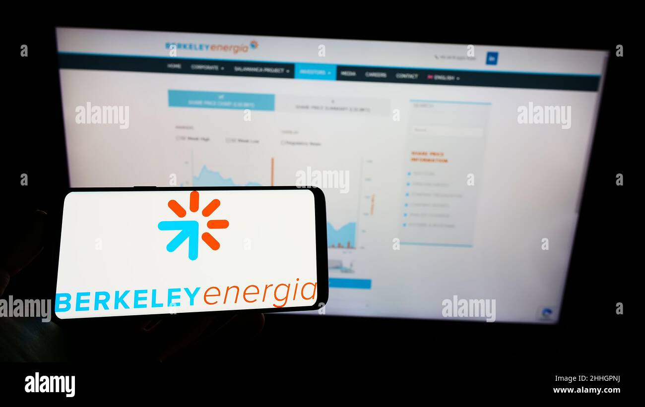 Person holding cellphone with logo of British energy company Berkeley Energia Limited on screen in front of webpage. Focus on phone display. Stock Photo