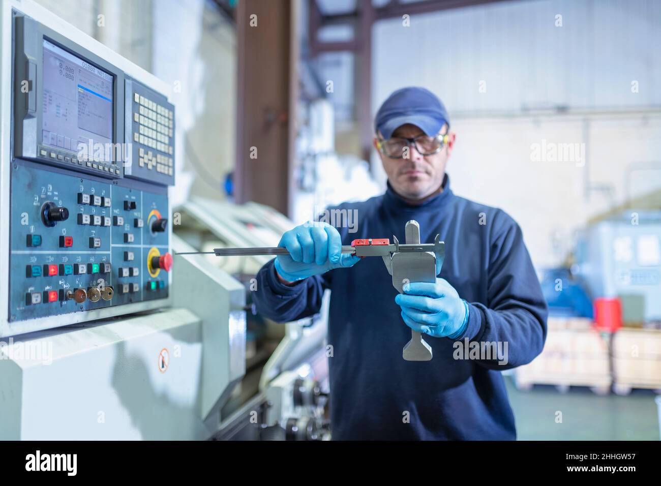 Engineer measuring titanium blanks in industrial forge Stock Photo