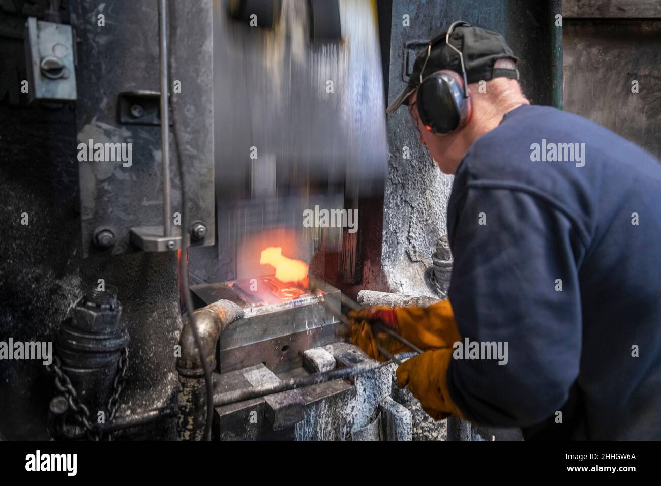 Engineer forging titanium parts in hammer press in industrial forge Stock Photo